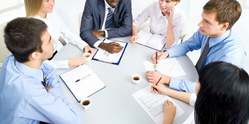 5-steps-to-effective-project-management_ team sitting at a table conducting project management meeting