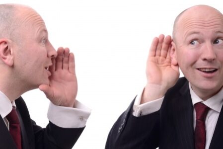 Businessman-Listening Man with his hand cupping his ear as another identical man cups his mouth saying something to him
