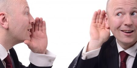 Businessman-Listening Man with his hand cupping his ear as another identical man cups his mouth saying something to him