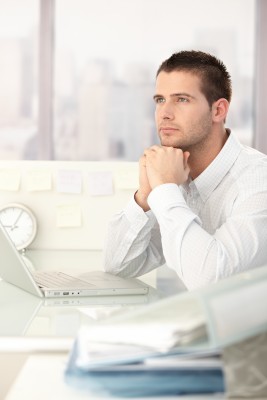 Businessman-daydreaming man looking off into the distance at his desk