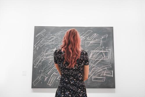 Do you know what an art director does? Here’s a snapshot into a typical day. Woman looking at art.