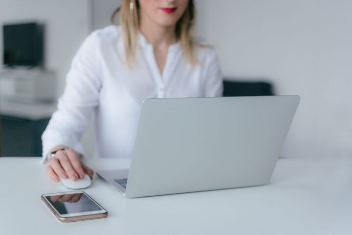 Recruitment-Best-Practices woman at a laptop with her phone on the desk
