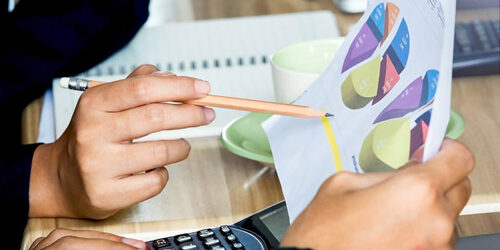 Sales and marketing need to work together to maximize lead generation. People looking at graphs on paper at a desk