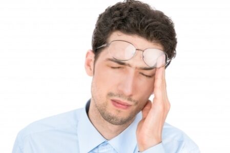 Stressed-Man Man rubbing his heads pushing his glasses up onto his forehead