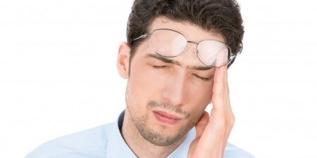 Stressed-Man Man rubbing his heads pushing his glasses up onto his forehead