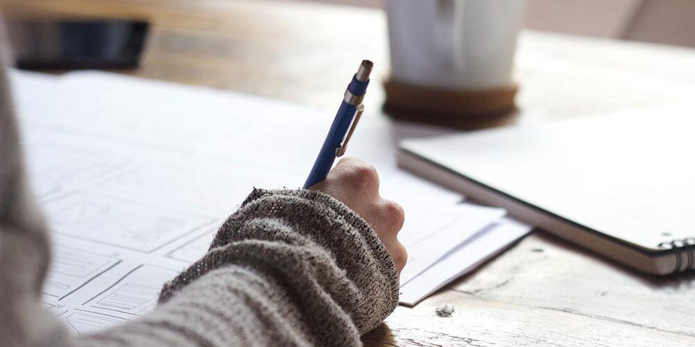 Content Writing vs. SEO Writing vs. Copywriting Jobs: What’s the Difference? coffee on desk with person writing on papers