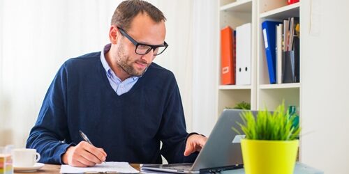 A marketer's job is colorful, to say the least. man writing on a clipboard as he scrolls on his laptop