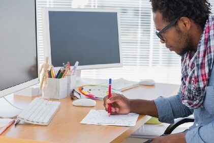 According to the Bureau of Labor Statistics, the graphic design job market is projected to grow 7% in the next few years, and creative job seekers can expect some tough competition. man drawing on a piece of paper at his desk