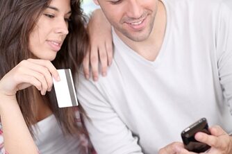 Are shoppers really relying on mobile? Man looking at his phone as a girl sits next to him holding a credit card