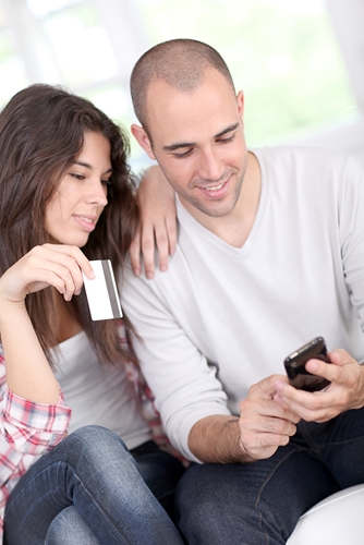 Are shoppers really relying on mobile? Man looking at his phone as a girl sits next to him holding a credit card