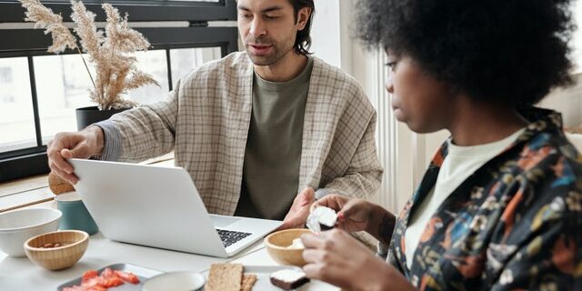 couple having breakfast with computer on table couple works at desk remote work after covid-19