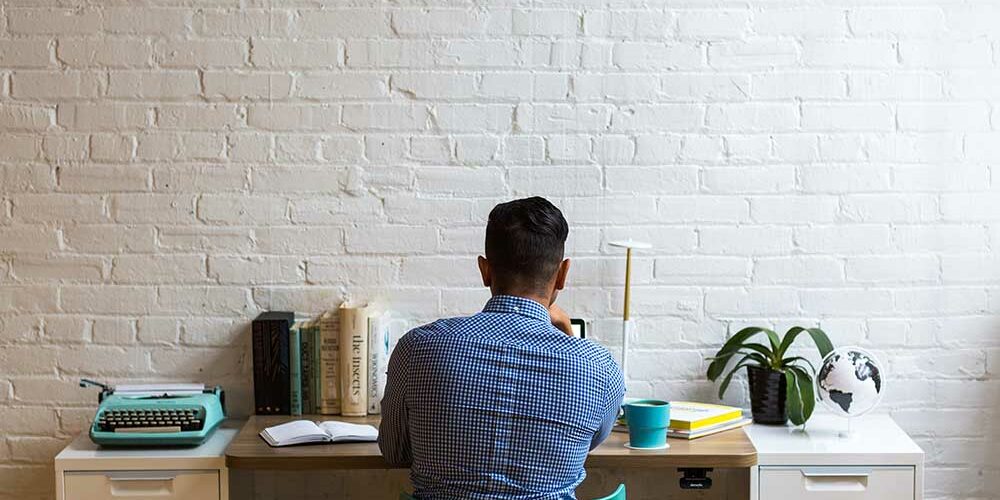 employee-writing-a-resignation-letter-at-a-desk-brick-wall employee-writing-a-resignation-letter-at-a-desk-brick-wall
