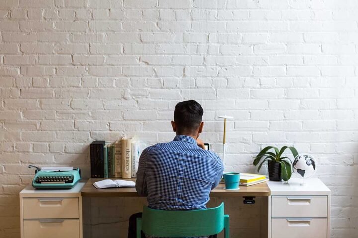 employee-writing-a-resignation-letter-at-a-desk-brick-wall employee-writing-a-resignation-letter-at-a-desk-brick-wall