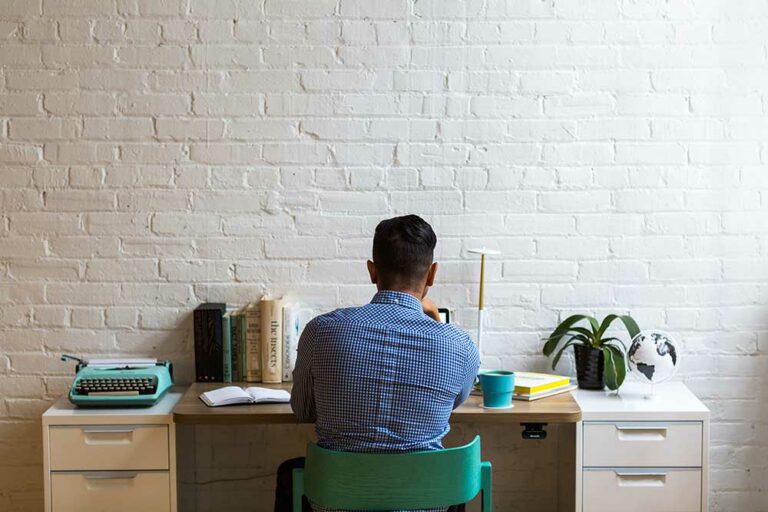 employee-writing-a-resignation-letter-at-a-desk-brick-wall employee-writing-a-resignation-letter-at-a-desk-brick-wall