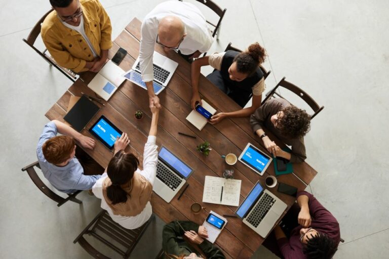 employees around a wooden table-hiring solutions_3 employees around a wooden table hiring solutions