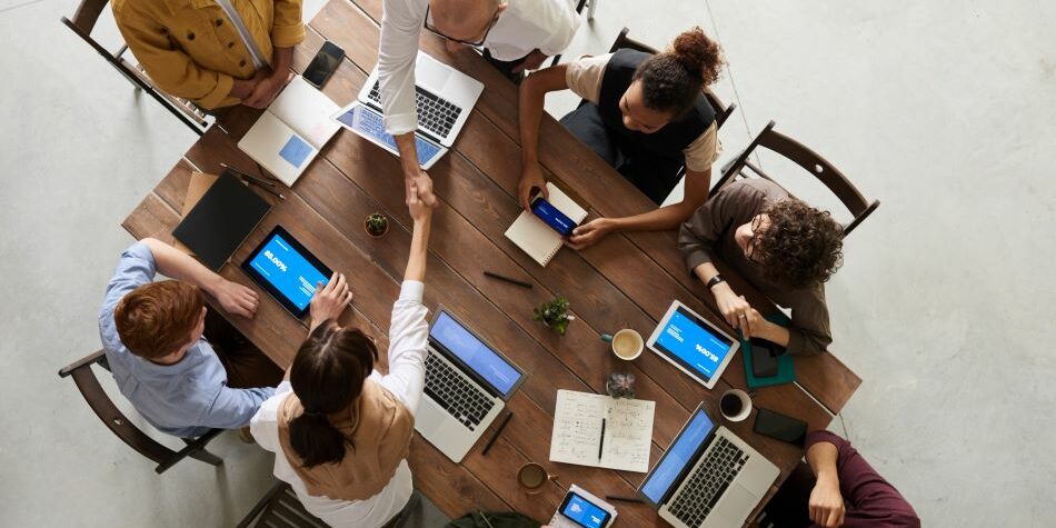 employees around a wooden table-hiring solutions_3 employees around a wooden table hiring solutions