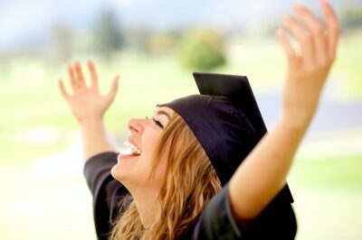 graduate woman celebrating her graduation with her hands in the air