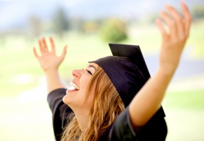 graduate woman celebrating her graduation with her hands in the air