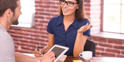 Here's how to formulate an answer that will give your interviewer enough information without damaging your reputation as an employee. woman talking to a man as he listens and looks at his tablet
