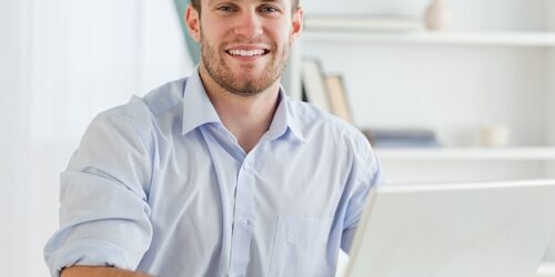 Here's how to start using inbound marketing to make customers come to you. man smiling at the camera as he works on a laptop