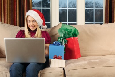 holidayjobsearch woman in a santa hat working on her laptop with gifts beside her