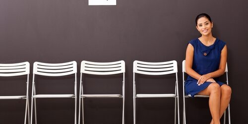 How to prepare an answer about your greatest strengths Woman sitting waiting to be interviewed with a row of empty chairs beside her
