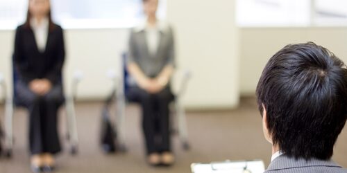 Interview etiquette is drilled into the minds of job seekers years before they even begin searching for employment. two women sitting to wait for an interview with the boss calling their name