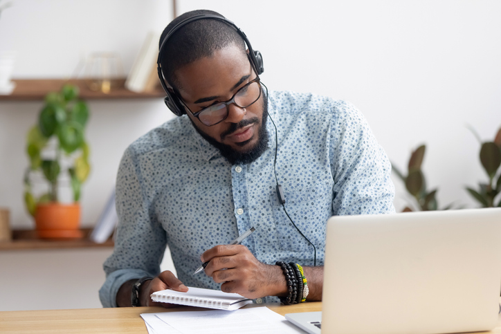 Focused african businessman in headphones writing notes watching webinar man at computer writing on note pad_job search tips