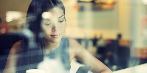 Make social HR more mobile in 2014 woman looking at her phone in a coffee shop