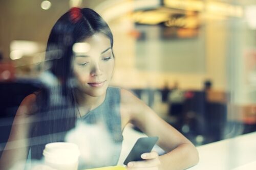 Make social HR more mobile in 2014 woman looking at her phone in a coffee shop