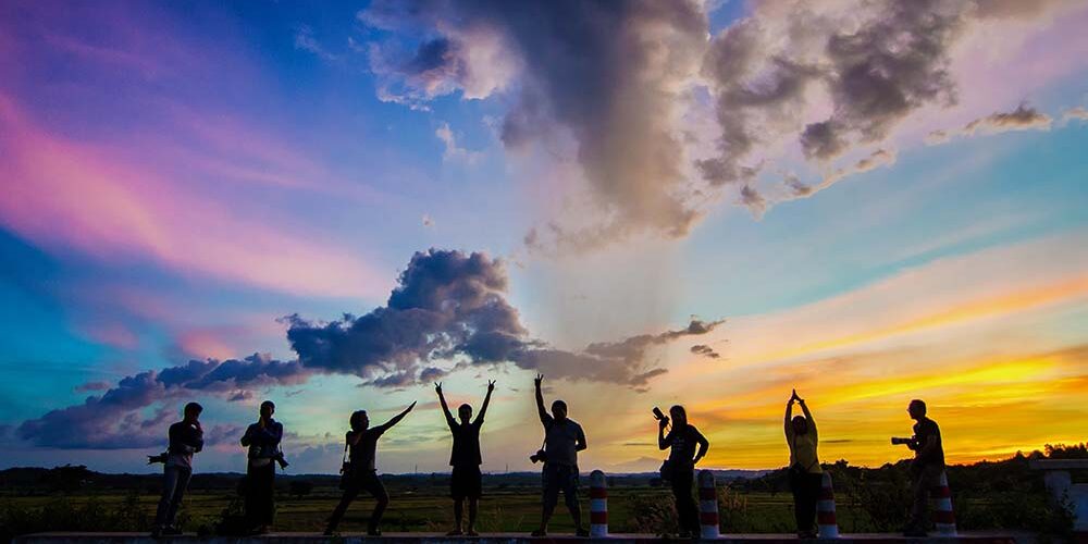 millennials Group of 8 people posing in front of a colorful sunset