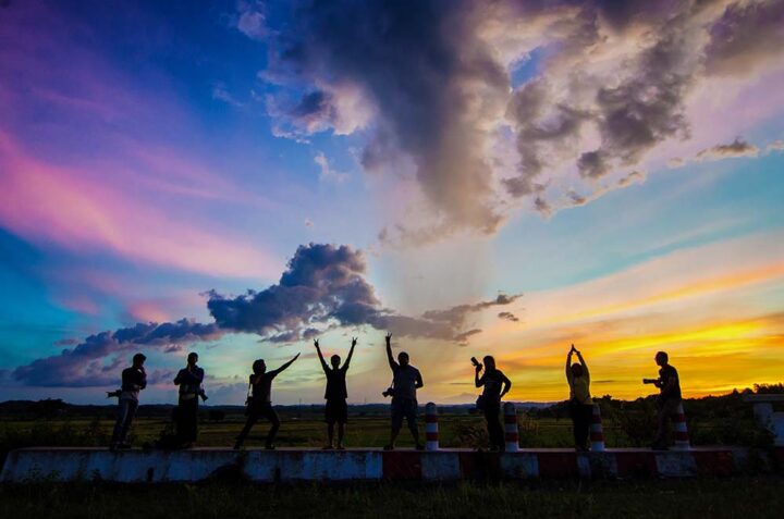 millennials Group of 8 people posing in front of a colorful sunset