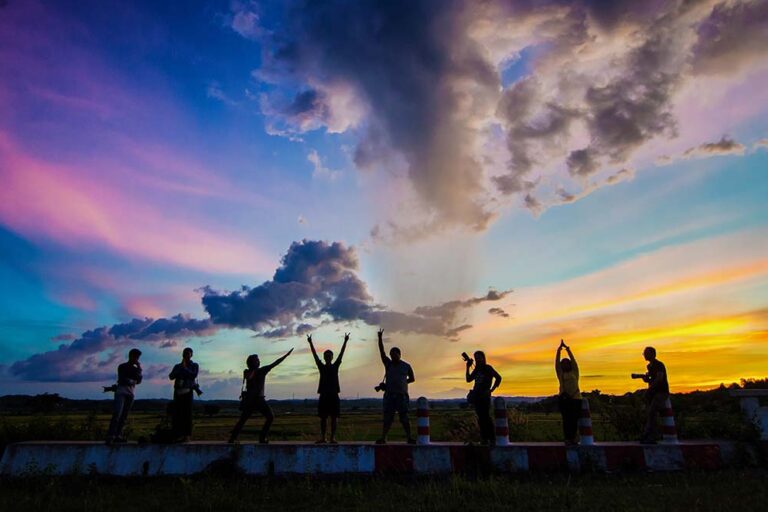 millennials Group of 8 people posing in front of a colorful sunset