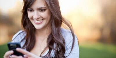 mobile woman smiling at her phone outside
