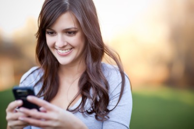 mobile woman smiling at her phone outside
