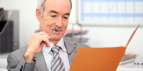 Perfect your resume like a pro Man with his glasses in his mouth as he look in folder