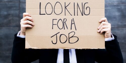 Realize the errors of your employment-seeking ways Man holding up a cardboard sign saying he is looking for a job in front of his face as he is dressed in a suit