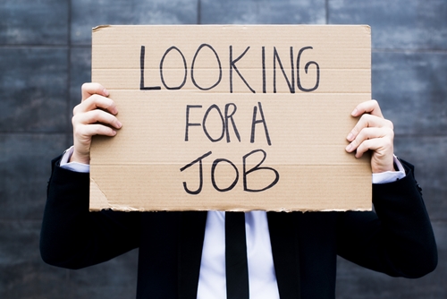 Realize the errors of your employment-seeking ways Man holding up a cardboard sign saying he is looking for a job in front of his face as he is dressed in a suit