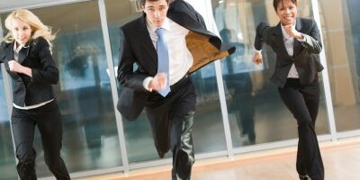 running 3 business professionals running down a hallway