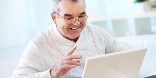 SEO value battle between paid search and organic search Man smiling as he works on his laptop