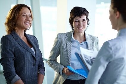 The success or failure of a project depends heavily on the quality and competence of a team's manager. Make sure you embody these qualities if you see project management in your future. two women smiling at another as they talk in an office setting