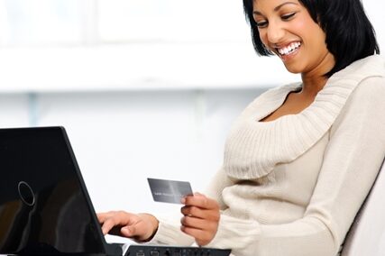 Tips for improving conversion rates Woman on a laptop smiling at her credit card