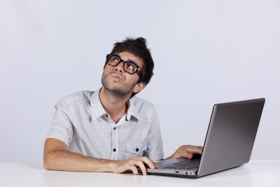 webdev man with a pondering face as he working his laptop looking up
