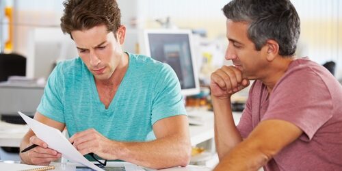 two men looking at paperwork in a bright office