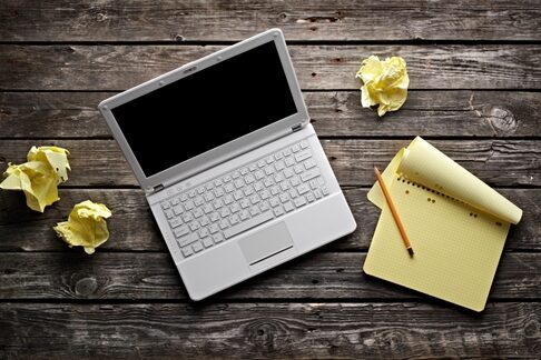 Why your website may be failing Overhead view of a laptop and a notebook sitting on a wooden table
