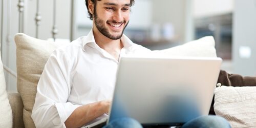 Writing a strong cover letter has always been a concern for job-seekers. With the digitization of networking and employment applications, not to mention the invasion of email, the stakes are now higher than ever – and most people are confused as to where the cover letter fits in to the recipe. man smiling as he works at his laptop on his couch