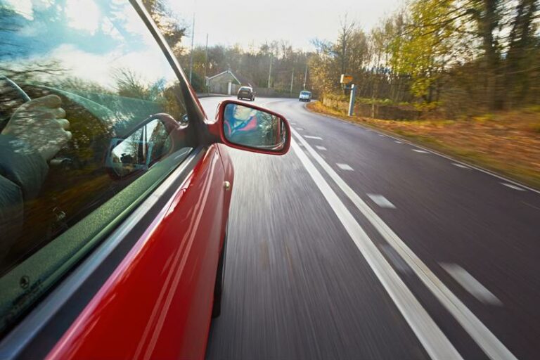 x_0_0_0_14109972_800 side of a red car driving down a road in the fall