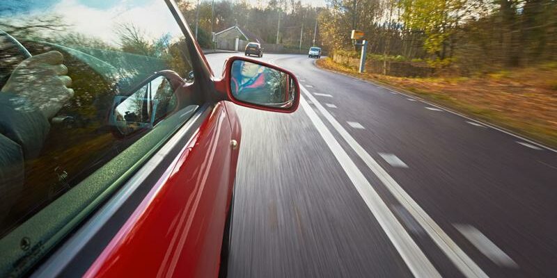 x_0_0_0_14109972_800 side of a red car driving down a road in the fall