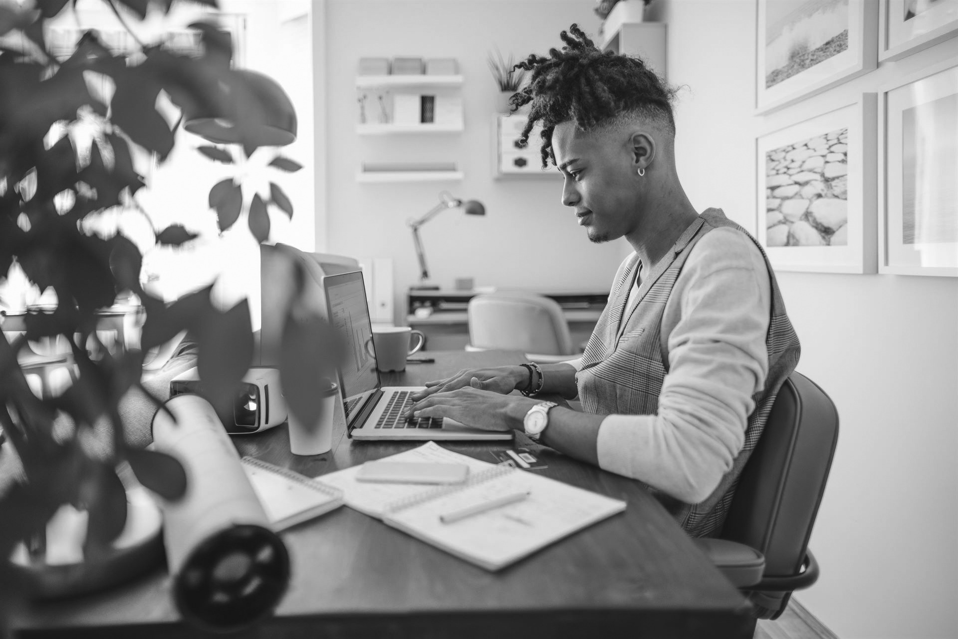 iStock-1226997723 Side view of a young man working at his desk on his laptop.