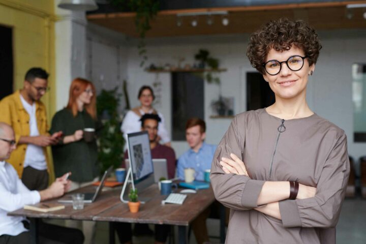 Successful woman CMO with her arms crossed in front of her team